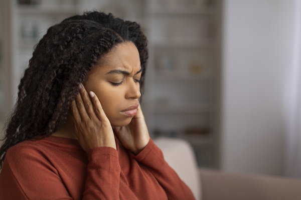 Stressed young black woman holding her jaw suffering TMJ