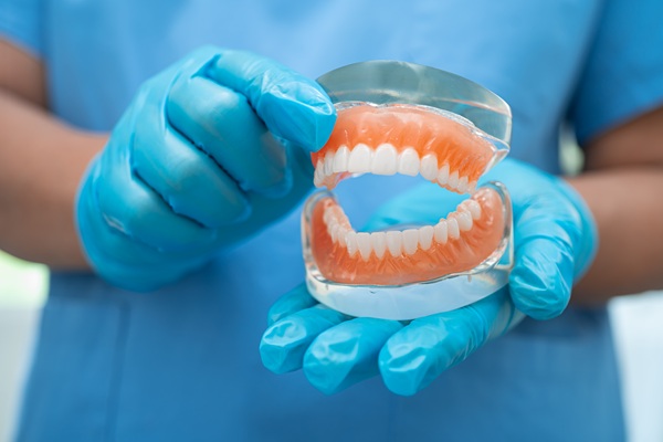 Denture, dentist holding dental teeth model to study and treat i
