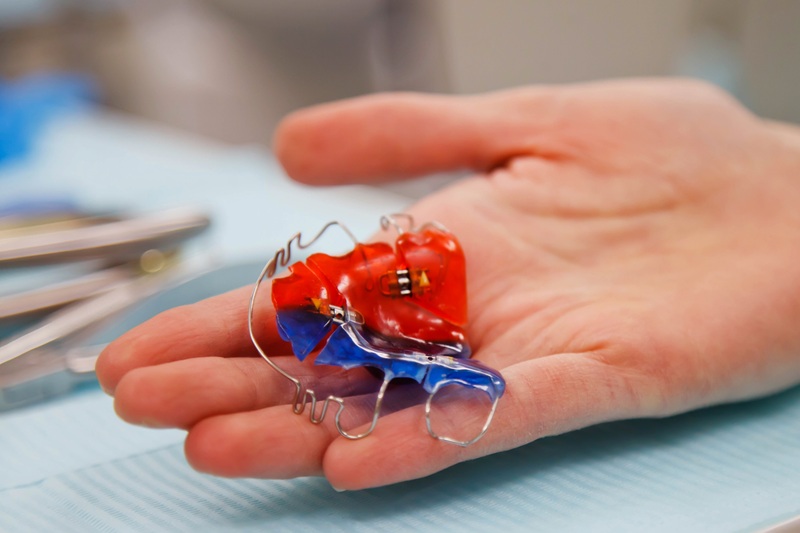 Removable clasp prosthesis in dentist's hand over medical table. Dental prosthesis in hands of doctor close-up. Dentist holds dental bridge. Dentist's office for prosthetics of false teeth. Copy space