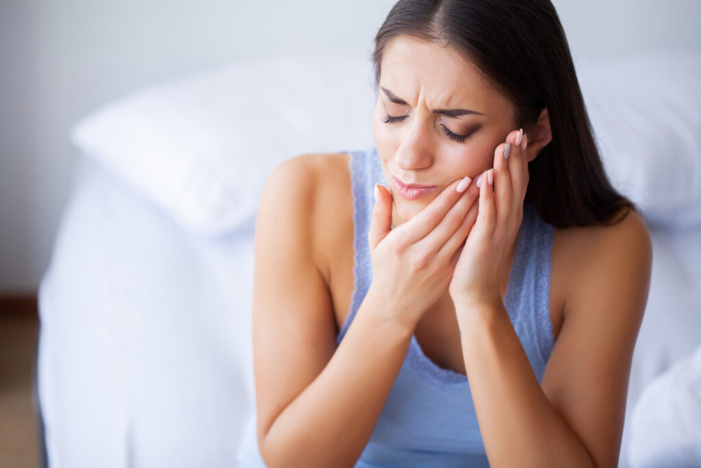 Woman experiencing jaw pain from grinding teeth in sleep