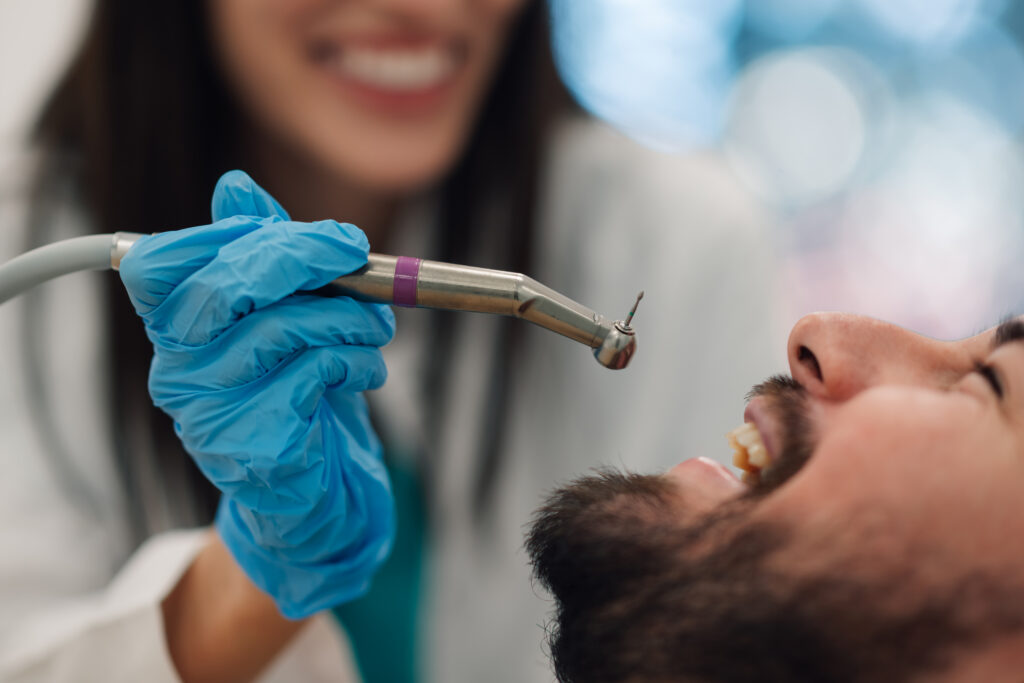Dentist using a dental drill to examine a patient's teeth, illustrating a checkup relevant to whether Medicare covers dental care