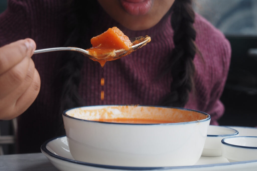 Person eating soft vegetable soup from a spoon, a gentle food option for what to eat after wisdom teeth removal